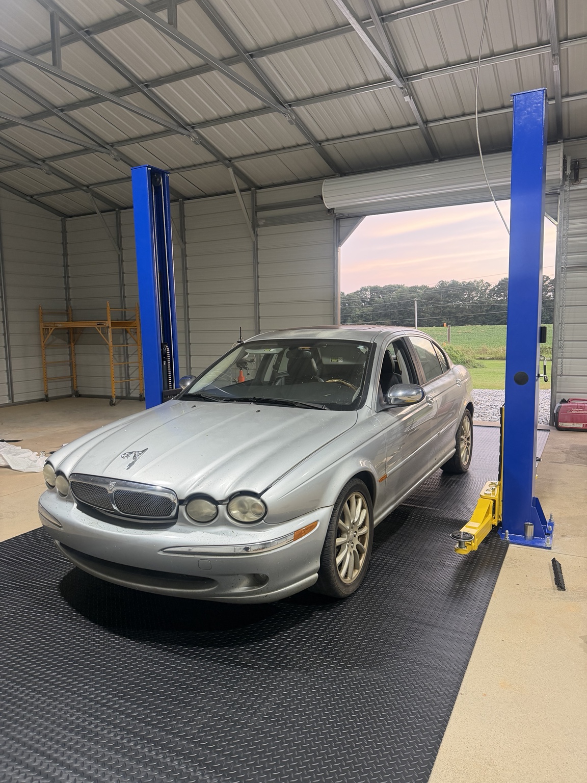 Jaguar sedan positioned at a lift inside the shop